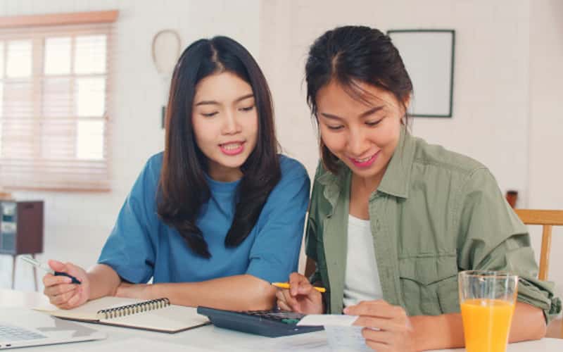 Women sitting looking at finances on paper before getting a vehicle loan